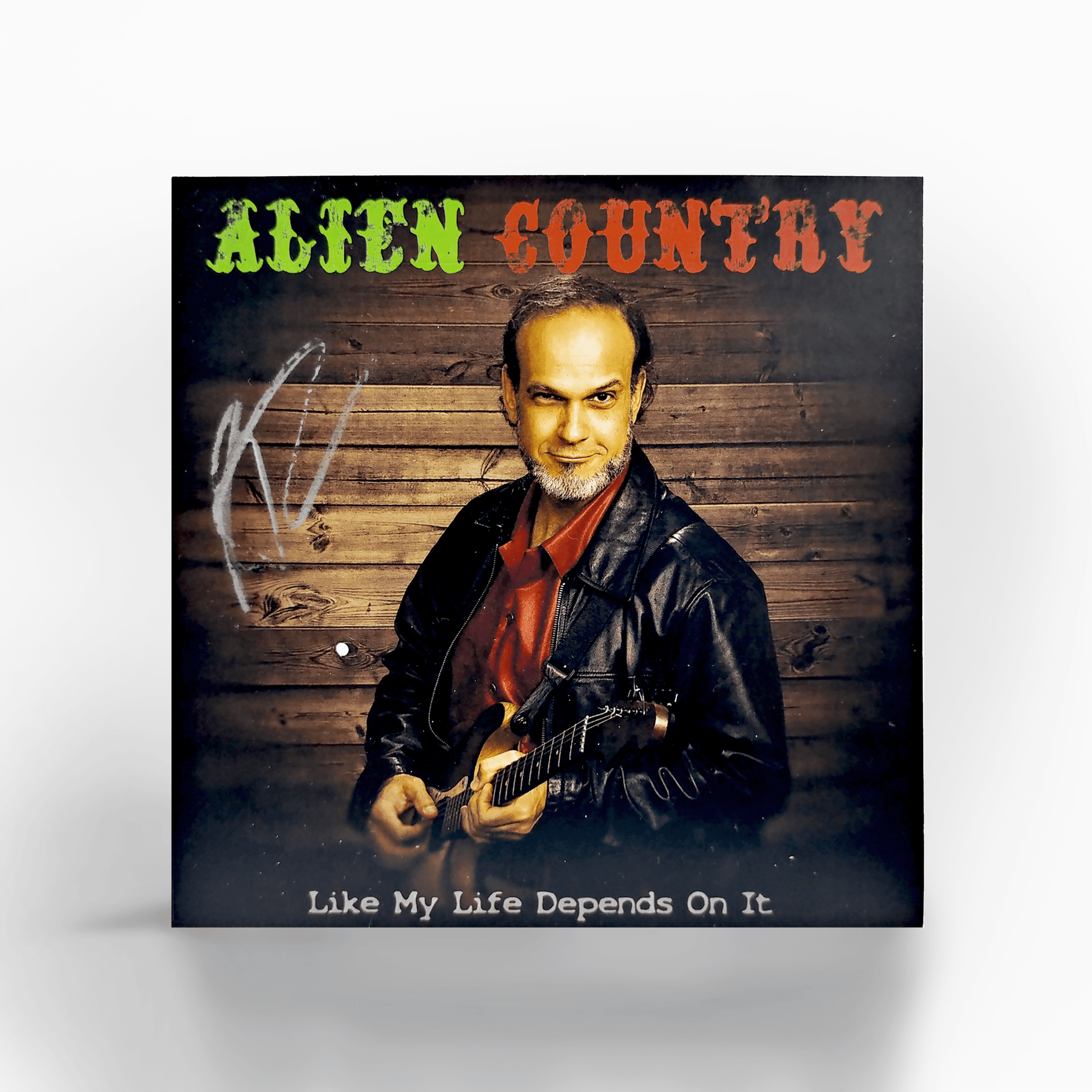 A photo of a CD and it's sleeve. The Sleeve has a picture of Liam Marcus holding an electric guitar. The CD art is a picture of Liam Marcus standing on a scenic  highway with mountains in the background. Scifi country rock