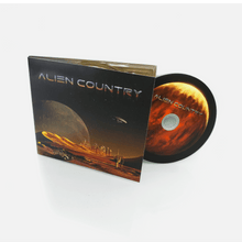 Load image into Gallery viewer, Alien Country Album cover - a red planet with sand dunes futuristic city on the horizon with alien moon and flying saucer high above. An antique pickup truck from Earth is driving along a dirt road which leads to the city.